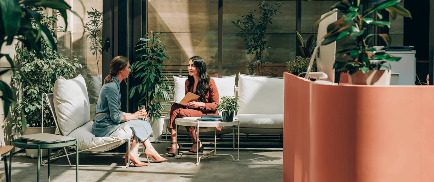 Two professionals discuss an invoice in a modern reception area with plants